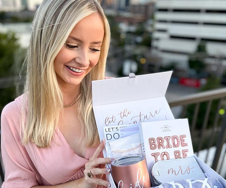 Bride holding the Maeven Signature Bridal Box, showcasing its elegant packaging filled with luxurious wedding planning items.