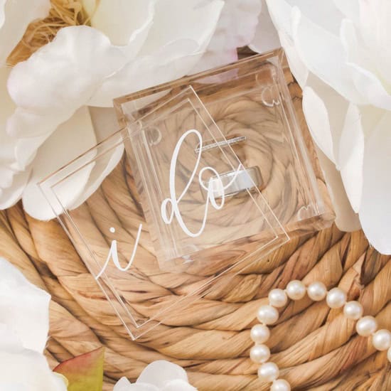 Clear acrylic ring box with 'I Do' inscription, perfect for displaying and photographing wedding rings, featuring a sleek design and customizable interior for added decorative touches